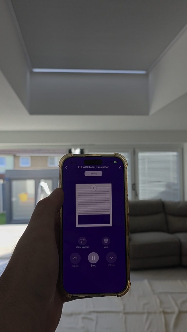 Smart App Controlled Roof Lantern Blind | TrueShade Interiors Solar powered roof lantern blind fully extended above a living room, with smart app controls displayed on a smartphone in Corby, Northampton