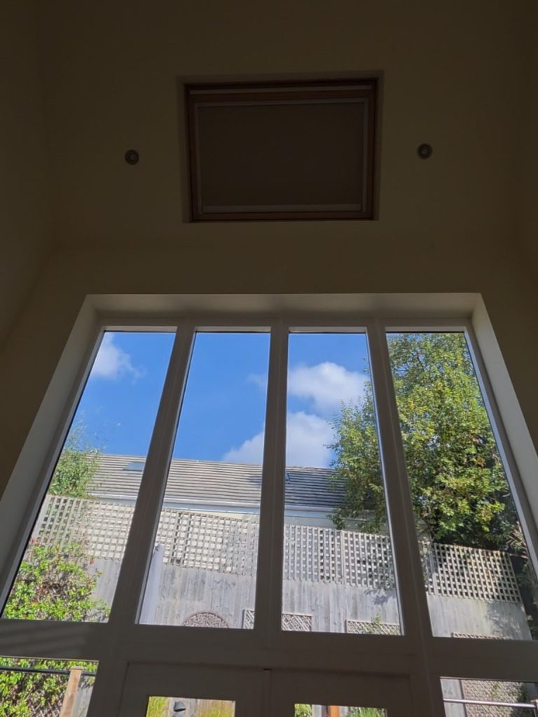 High-Level Solar VELUX Blind | Great Oxendon Solar powered VELUX blind installed in a high-level roof window above tall glazing in Great Oxendon, Northamptonshire